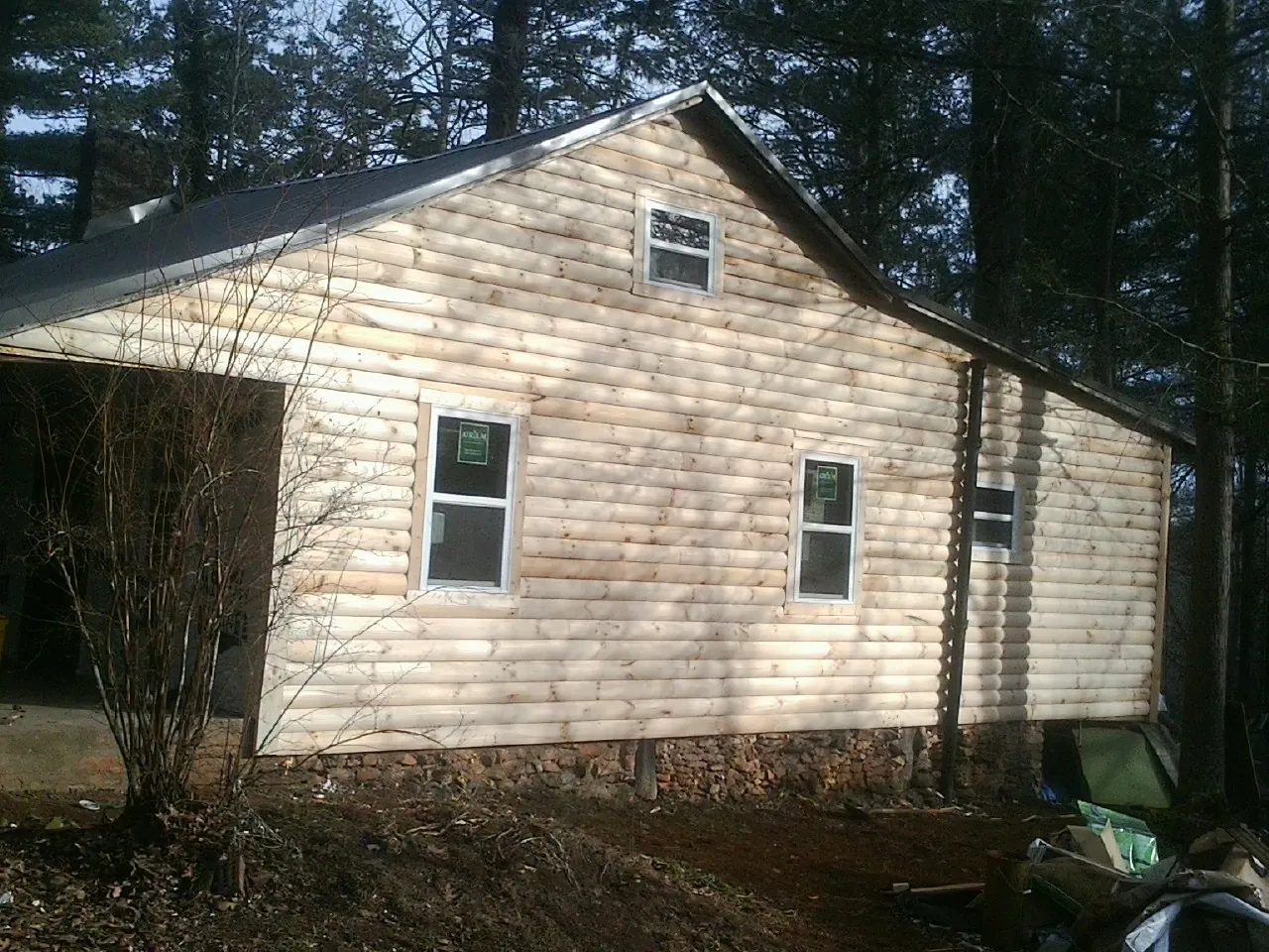 New log siding and dark metal roofing on a gable end in Montague